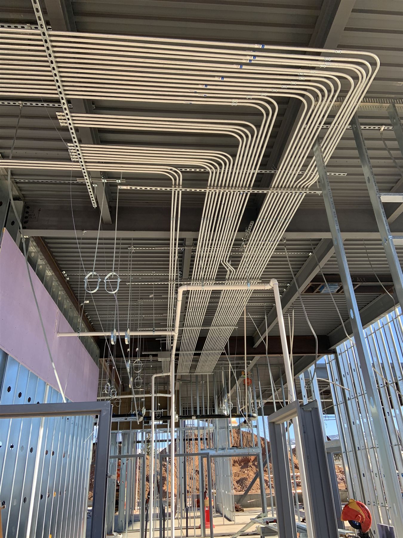Rows of bent EMT conduit racked across a commercial building ceiling